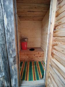 eine kleine Holzsauna mit einem roten Eimer darin in der Unterkunft Wilderness Cabin Hukkajärvi (no electricity,no running water) in Karesuvanto
