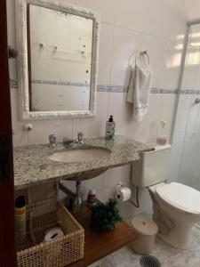 ein Badezimmer mit Waschbecken, Toilette und Spiegel in der Unterkunft Casa Oceano Psicina área gourmet pertinho do mar in São Sebastião