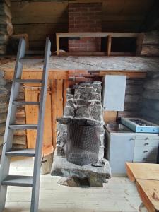 einen Steinkamin in einer Küche mit einer Leiter in der Unterkunft Wilderness Cabin Hukkajärvi (no electricity,no running water) in Karesuvanto