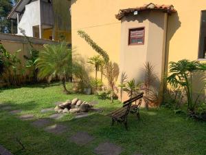 Eine Bank, die im Gras neben einem Gebäude steht in der Unterkunft Casa Oceano Psicina área gourmet pertinho do mar in São Sebastião