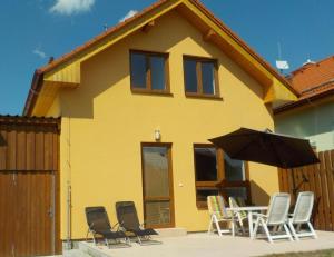 a group of chairs and an umbrella in front of a house at Casa Maika in Frymburk