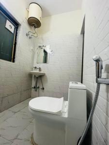 La salle de bains blanche est pourvue de toilettes et d'un lavabo. dans l'établissement Hotel Badal Inn - Safdarjung Enclave, à New Delhi