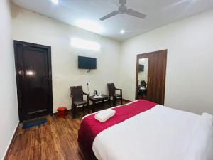 a bedroom with a bed and two chairs and a television at Hotel Badal Inn - Safdarjung Enclave in New Delhi