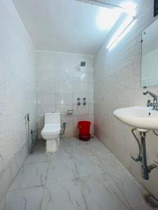 a white bathroom with a toilet and a sink at Hotel Badal Inn - Safdarjung Enclave in New Delhi