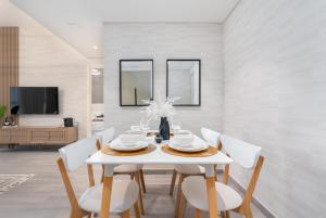 comedor con mesa blanca y sillas blancas en Tamm - Noor 2 Tower en Dubái