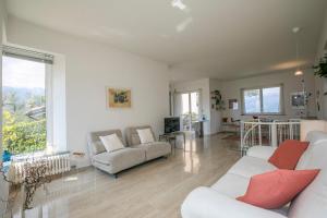a living room with white furniture and a large window at Residenza due Laghi Pool Lake View in Brezzo