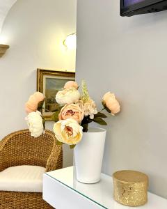 eine weiße Vase mit rosa Blumen auf dem Tisch in der Unterkunft Ex Monastero Pieno Centro storico in Bitetto