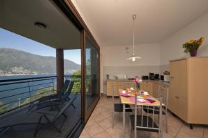 eine Küche mit einem Balkon mit einem Tisch und Stühlen in der Unterkunft Va Pensiero sul lago Stunning View in Tronzano Lago Maggiore