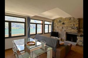 uma sala de estar com um sofá e uma lareira de pedra em Riflessi sul lago apt – Laglio em Laglio