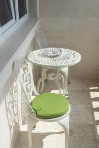 a white table and chairs with a green seat at Luxurious Mamu Apartment in Batumi