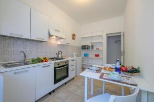 uma cozinha com armários brancos e uma mesa em Casa Al Caprifoglio 600 Mt From Beach - Happy Rentals em Ispra