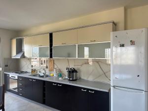 una cucina con armadi neri e frigorifero bianco di Durres beach home a Durrës