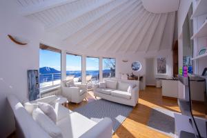 Una sala de estar con muebles blancos y grandes ventanales. en The Perfect View Loft - Happy Rentals, en Premeno
