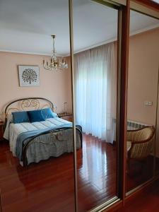 een slaapkamer met een bed met blauwe kussens en een spiegel bij La Casa de Ana in El Barco de Ávila