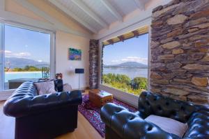sala de estar con sofá de cuero y ventana grande en Paradis Relais Pool,View,EV Recharge- Happy Rentals, en Belgirate