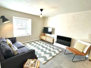 un soggiorno con un divano e una televisione di Palms 2 - Central, 5 mins walk to beach + parking! a Newquay