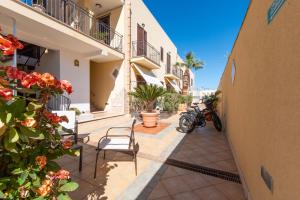 un patio en un edificio con sillas y flores en Room and Breakfast Aloe, en San Vito lo Capo