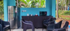 a blue room with a refrigerator and chairs at Crop and Food Farm Stay in Ferokh