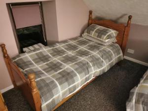 a bedroom with a bed with a plaid comforter at Aughnahoy Staycations Portglenone in Portglenone
