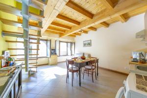 una cocina con mesa y sillas y techos de madera. en Casa Baroni few min from Orta Lake, en Madonna del Sasso
