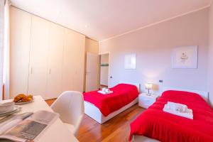 a bedroom with two beds with red sheets and a table at Appartamento Il Golfo Lake View - Happy Rentals in Laveno