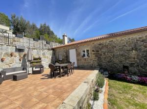 a patio with a table and chairs next to a stone building at YourHouse A Casa Da Corona casa rural in Ourense