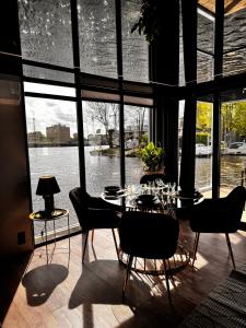 ein Esszimmer mit einem Tisch und Stühlen sowie einem großen Fenster in der Unterkunft Houseboat EnergyApart in Stettin