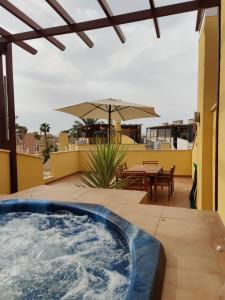 - un bain à remous sur une terrasse avec une table et un parasol dans l'établissement Casa del Sol - Vera Playa Laguna Beach, à Vera