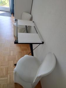 uma cadeira branca sentada ao lado de uma parede em Maison Champperbou em Haut-Vully