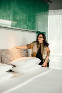 a woman standing next to a bed with pillows at Lido Palace - The Leading Hotels of the World in Riva del Garda