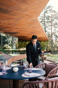 a man in a suit standing at a table at Lido Palace - The Leading Hotels of the World in Riva del Garda