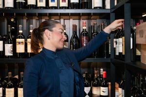 a woman standing in front of a shelf of wine bottles at Lido Palace - The Leading Hotels of the World in Riva del Garda