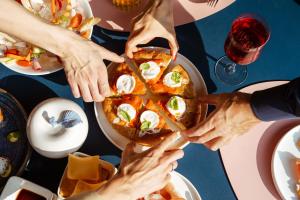 Un groupe de mains se rassemblant pour une pizza sur une table dans l'établissement Lido Palace - The Leading Hotels of the World, à Riva del Garda