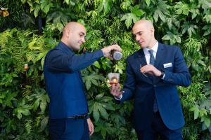 two men in suits standing in front of a hedge at Lido Palace - The Leading Hotels of the World in Riva del Garda