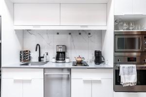a kitchen with white cabinets and stainless steel appliances at Glyn Rhosyn Loft in Stratford