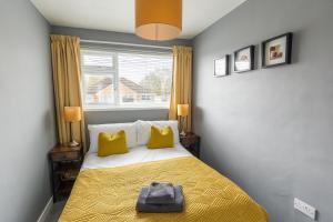 una camera da letto con un letto con cuscini gialli e una finestra di WOODFIELD ROAD - Two bed in Harrogate with cosy living room fire. a Harrogate