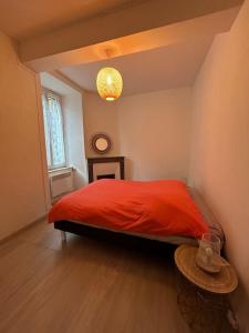 una camera con letto rosso e tavolo di Maison de village a Ussat