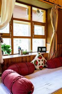 マナリにあるGharsa - Your Mountain Homeのベッドルーム1室(赤い枕のベッド1台、窓付)