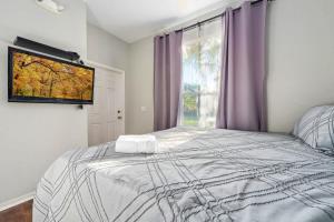 a bedroom with a bed and a window with purple curtains at Resort w Lazy River and Arcade 30mis to Disney in Davenport