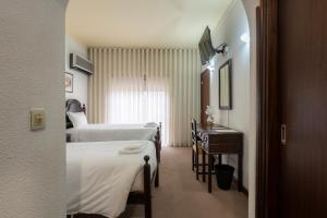 セロリコ・ダ・ベイラにあるHotel Mira Serraのベッド2台とテーブルが備わるホテルルームです。