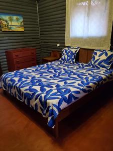 Una cama con sábanas azules y blancas y una ventana en Bungalow Chez Mouch Nosy Be 7 en Nosy Be