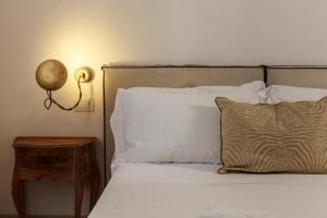 uma cama com almofadas brancas e um candeeiro sobre uma mesa em Embrace Sicily Guest House em Noto