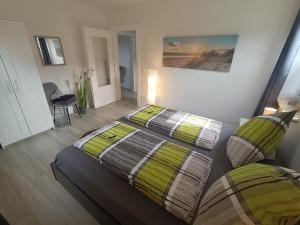 1 Schlafzimmer mit 2 Betten mit grünen und grauen Decken in der Unterkunft Küstenliebe in Wilhelmshaven