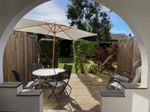 un patio con sombrilla, mesa y sillas en Vacances Sur Mer en Saint-Palais-sur-Mer