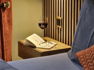 una copa de vino y un libro sobre una mesa con una cama en Ferienhof SchilfMeer - Fewo "Seepferdchen", en Dorf Körkwitz