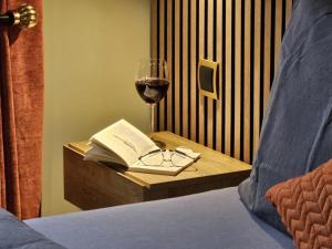 ein Glas Wein und ein Buch auf einem Tisch mit einem Bett in der Unterkunft Ehemaliger Bauernhof - Whg "Seepferdchen" - [#117813] in Dorf Körkwitz