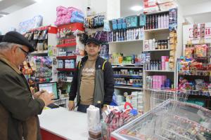 un hombre parado en un mostrador en una tienda en Hostel Asham en Panjakent