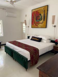 a bedroom with a large bed with a painting on the wall at Queen of Galle in Galle