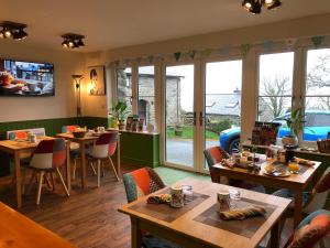 een restaurant met tafels, stoelen en ramen bij The Old Farmhouse B&B in Dyffryn