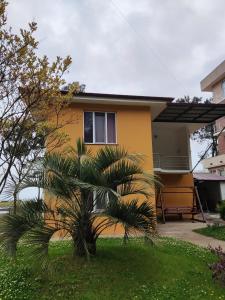 una casa gialla con una palma di fronte di Giomari a Shekhvetili